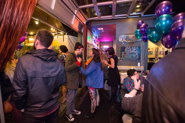Guests mingling at the Love Bomb 2017 event, vibrant decor with purple and teal balloons, illuminated atmosphere, showcasing community engagement for My Voice Music nonprofit.